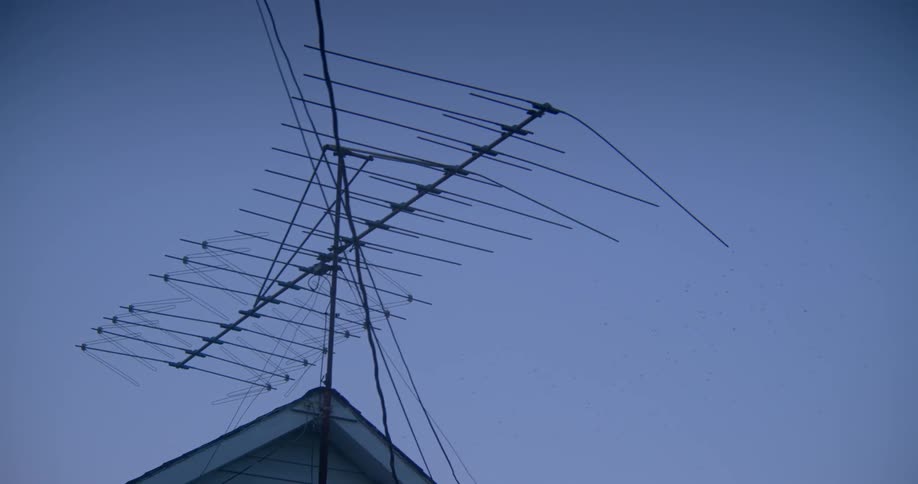 Tv antenna on a mast attached to a house on a clear day