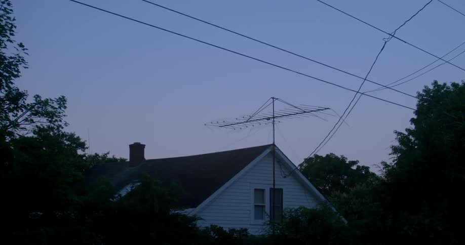 House in a rural area with power lines and a tv antenna