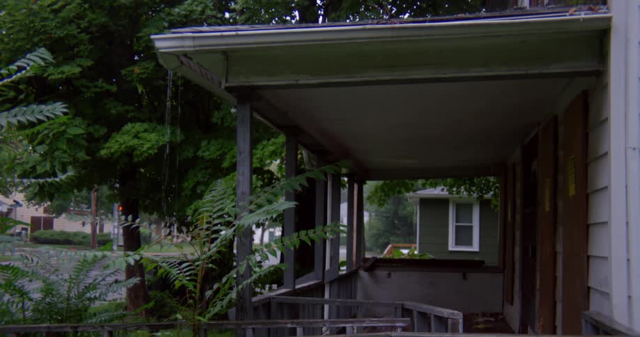 Cars drive past this house in the rain