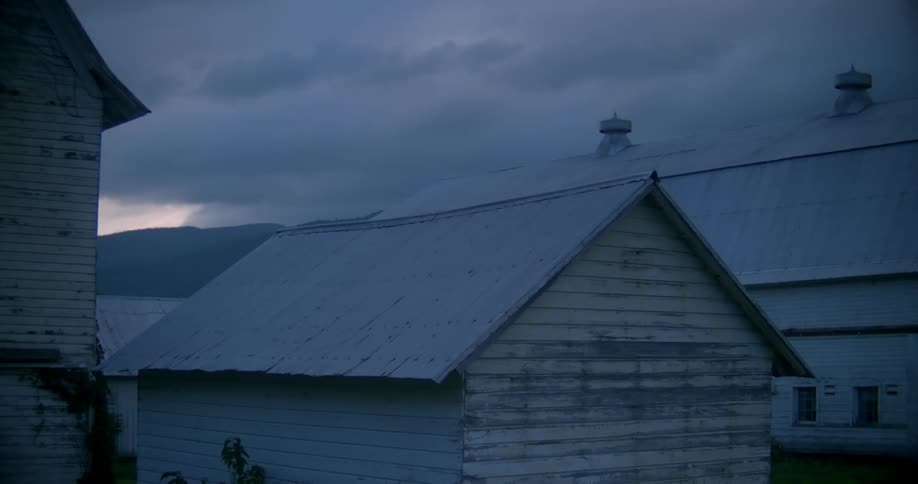 Dark clouds loom over a village at dawn