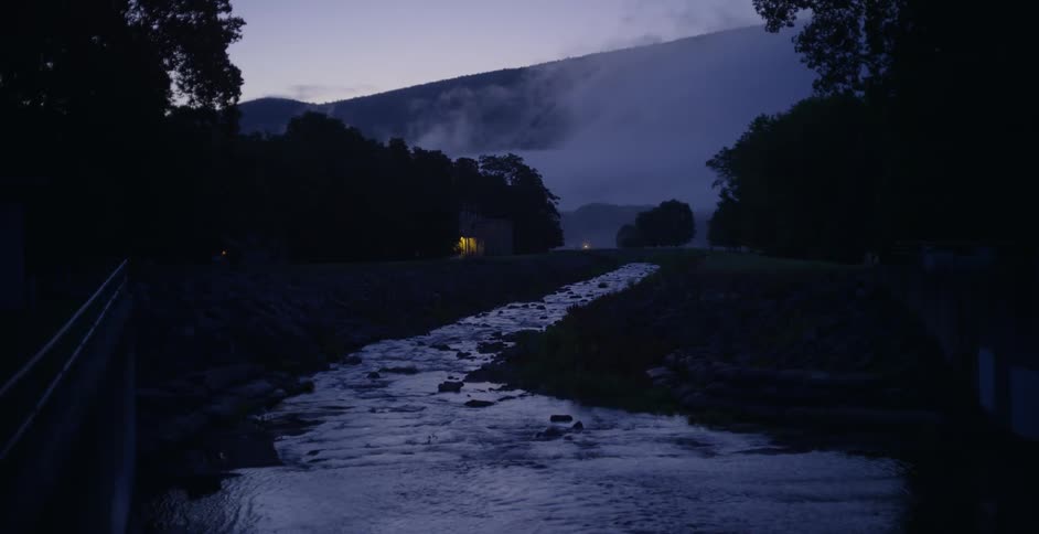 A creek runs past a building at dusk