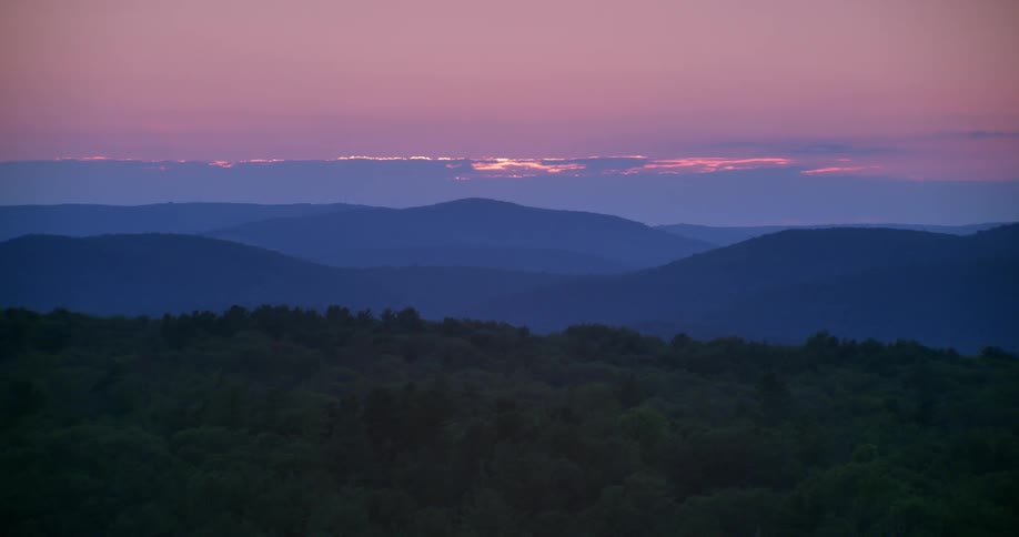 The sun is setting behind the mountains at dawn