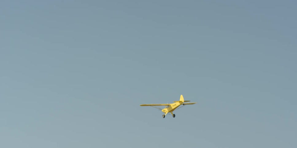A small aircraft flies in a clear and sunny sky