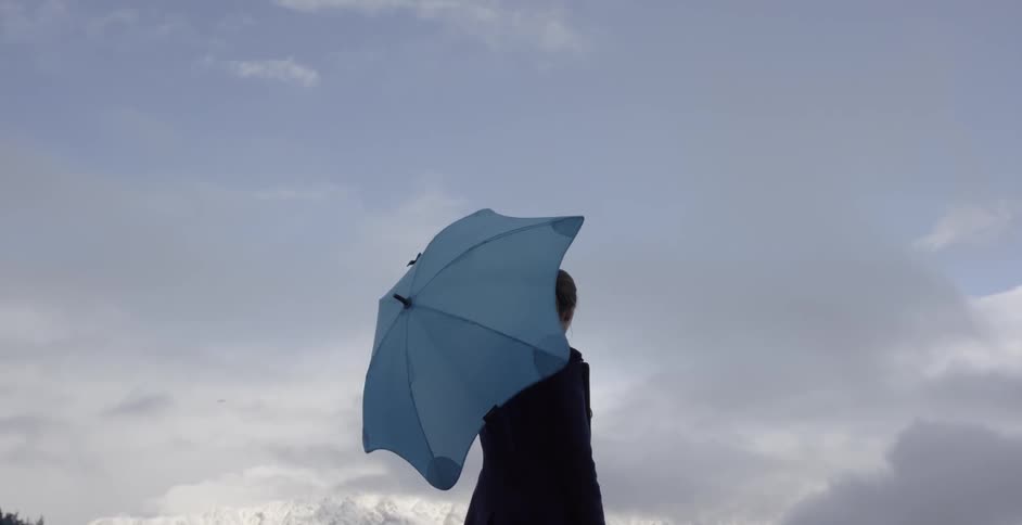 A woman twirls an umbrella while standing in the snowy mountains