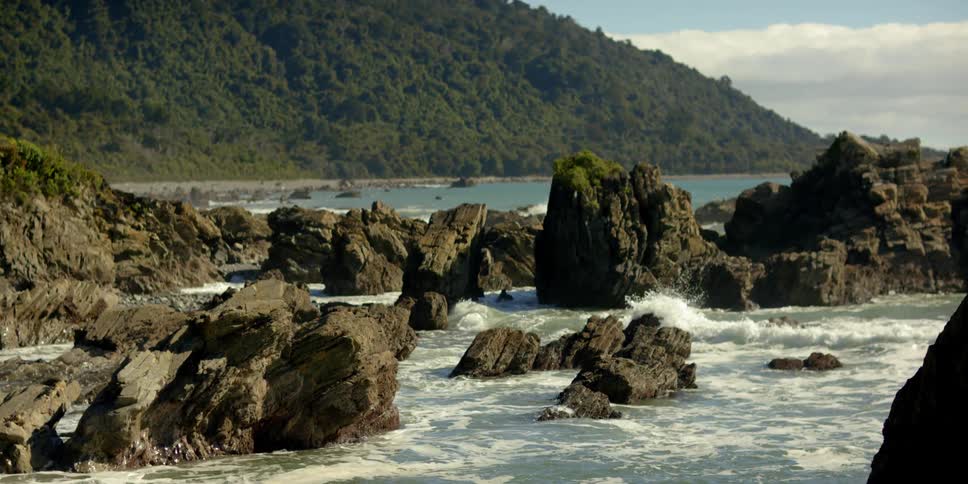 The waves crash against the rocks of the shore