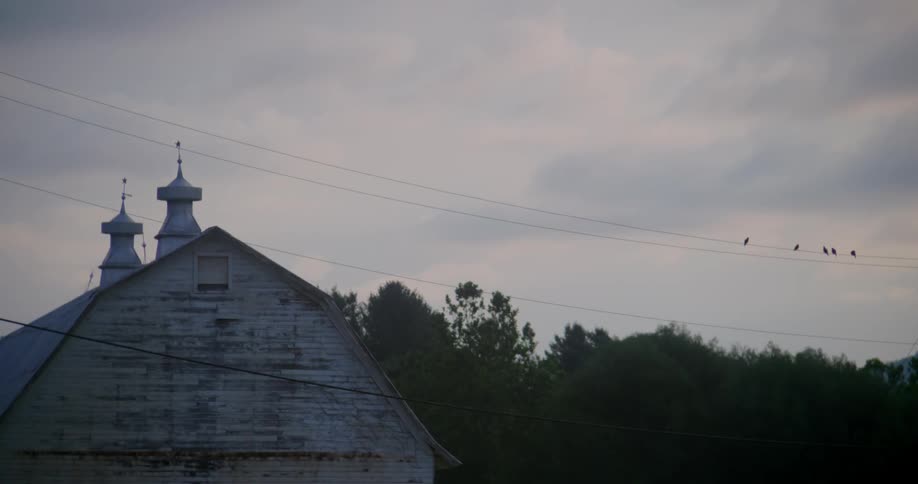 A large barn sits before trees