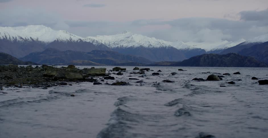 Water flowing to shore with mountains in the background