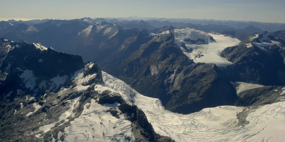 The mountain tops are covered with snow, ice, and jagged rocks
