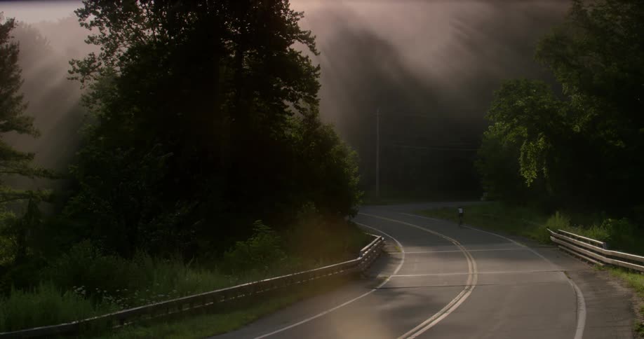 A bicyclist rides on a rural road