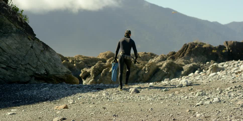 Diver running up a hill with some equipment