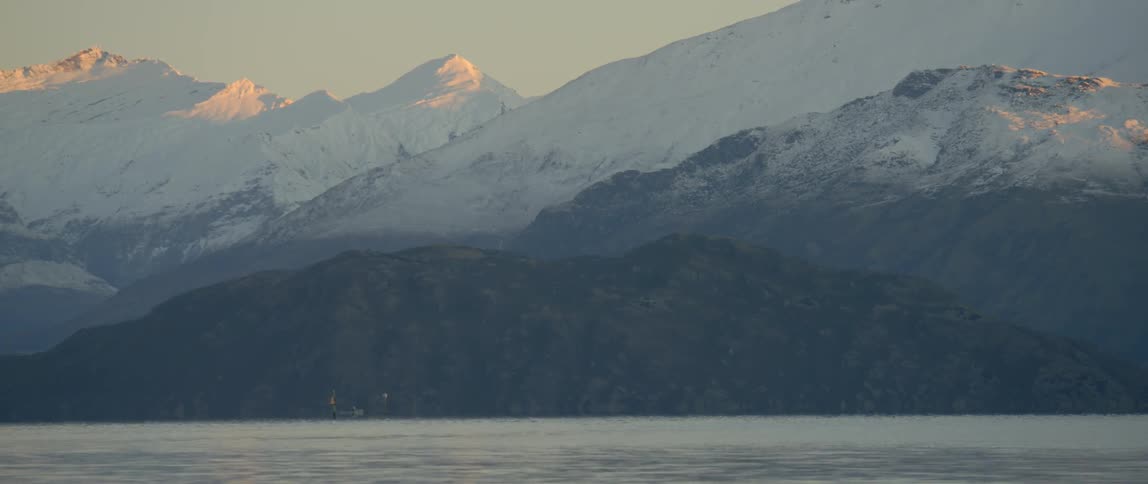 Water shimmers beneath the snow covered mountain peaks