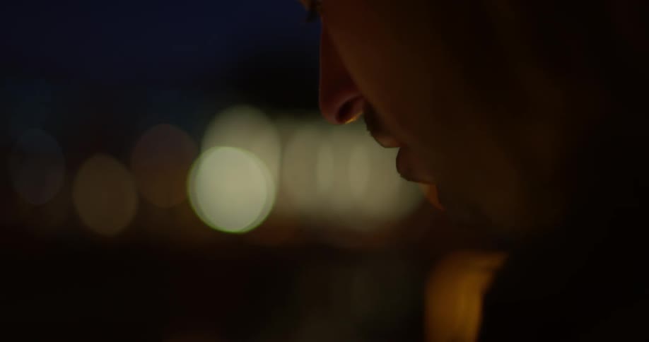 A man is wearing a hat outside at night