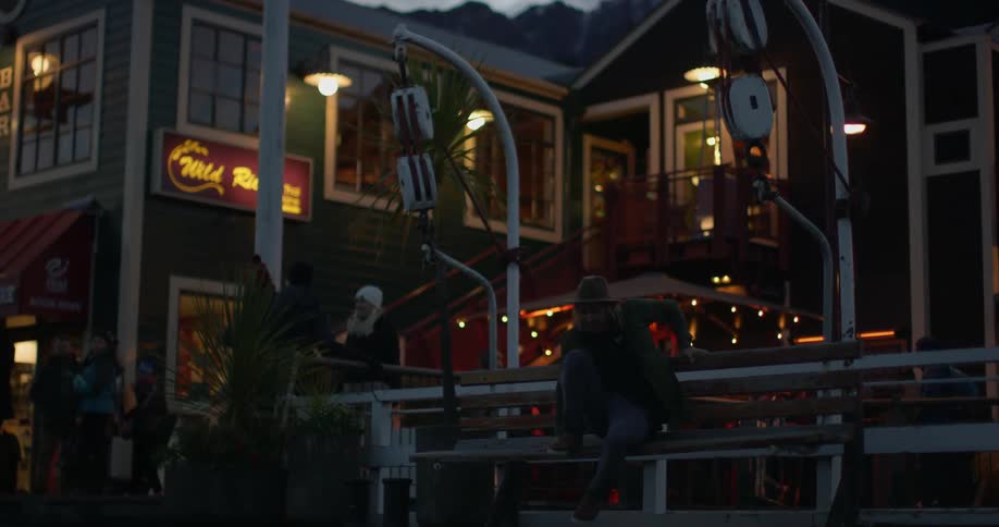 A man swings on a bench swing at night