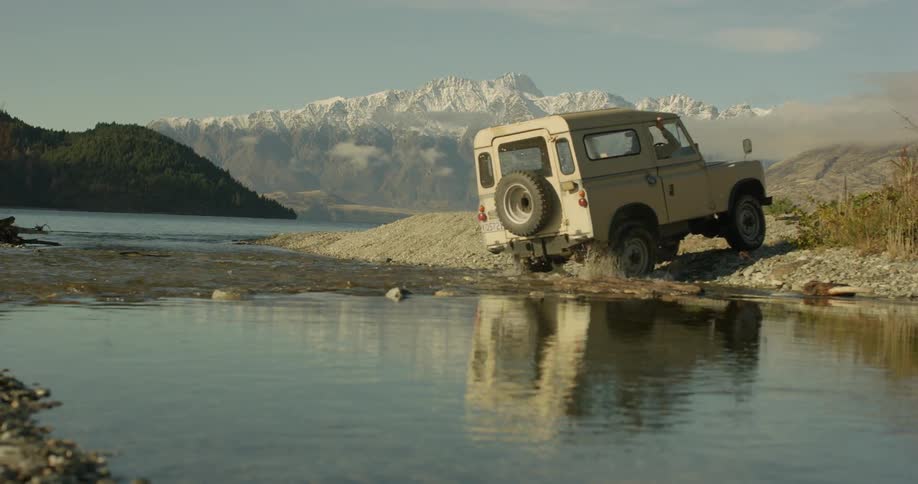 Jeep splashes through a shallow stream of water