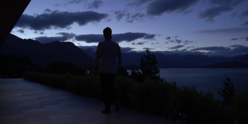 Silhouette of a man walking near a lake at sunset