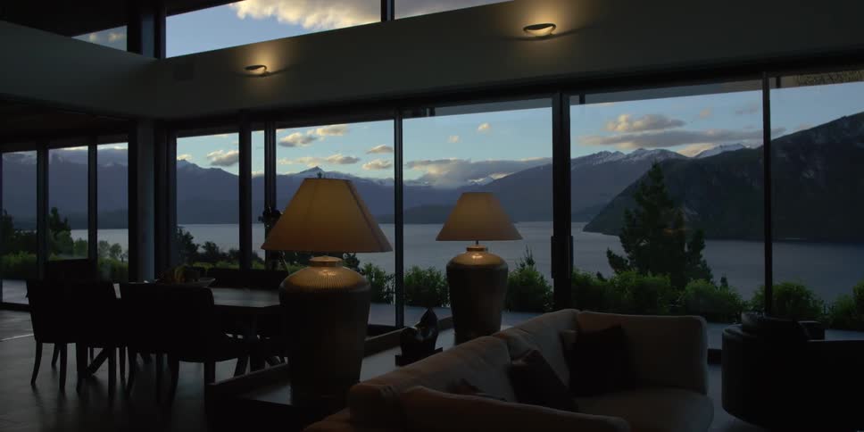 A mountain lake is seen through floor to ceiling windows in a house