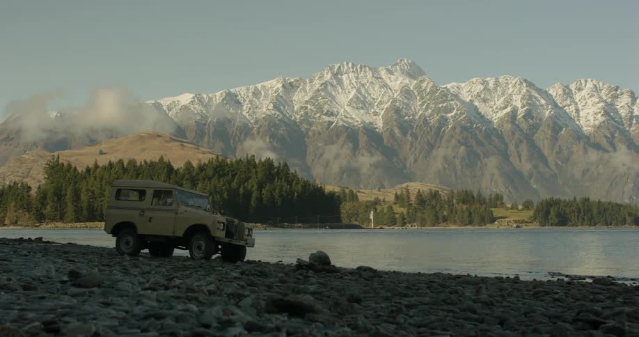 A vehicle drives up to a mountain lake