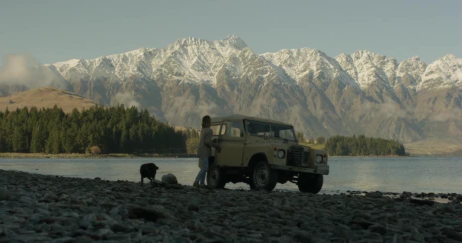 A man and his dog get out of a truck by the water