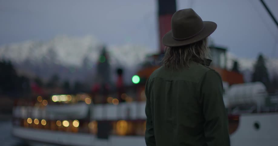 A man in a hat watches a boat