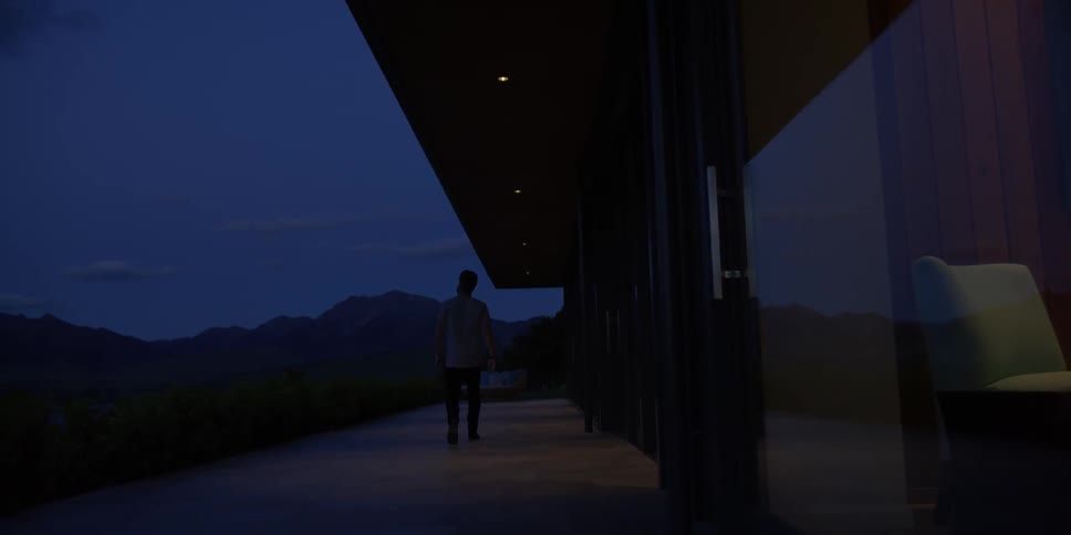 A man is walking along the outside of his home at dawn