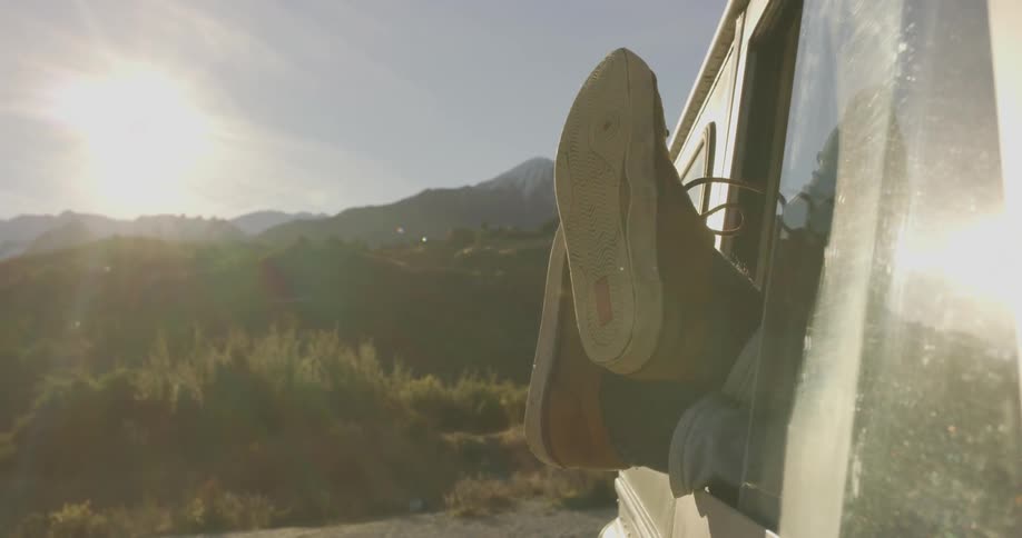 A person moves their feet hanging out a car window