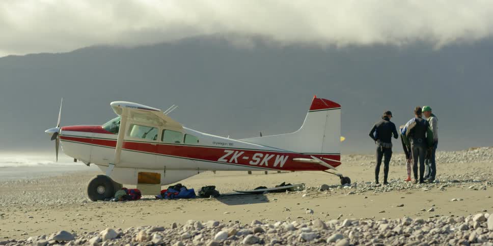 Group of people standing outside a small airplane talking