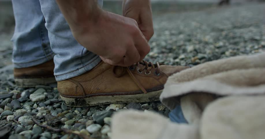 A man leans over to tie a shoelace