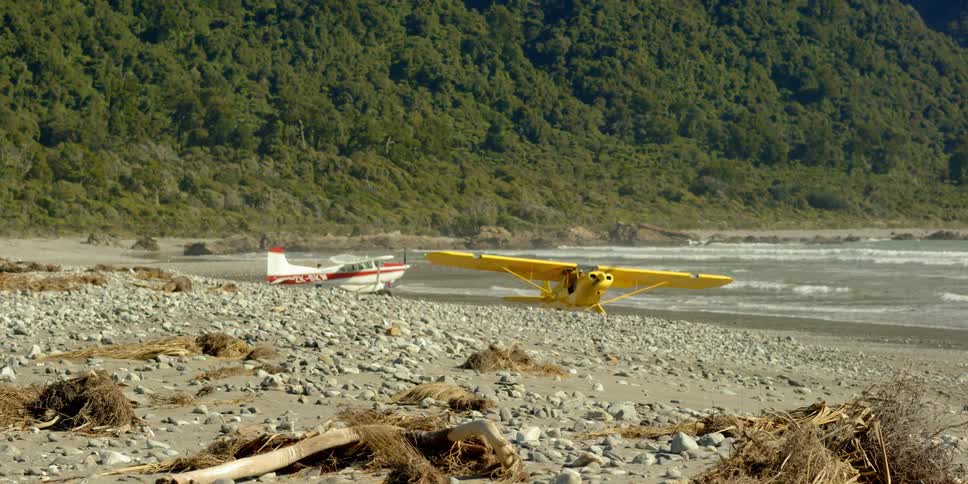 Small yellow airplane with spinning propeller near beach