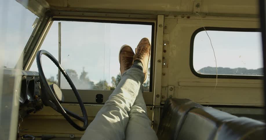 A person is resting in the car with their feet out the window