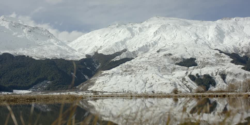 The calm lake is reflecting the snow covered mountain