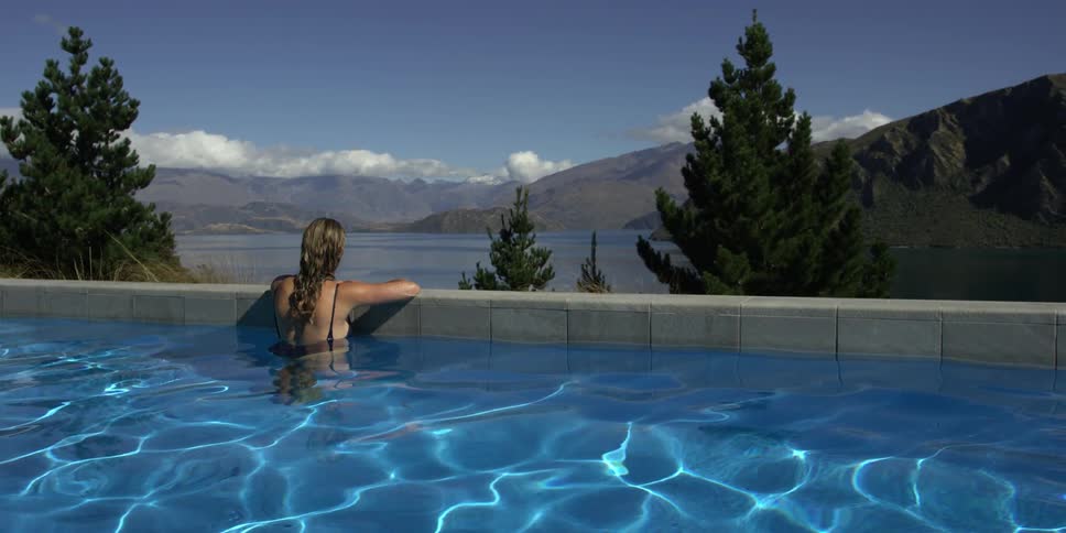 A woman is lounging in the pool leaning on the side