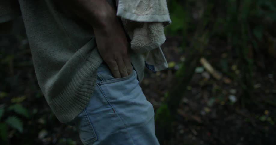 A man puts his hand in his front pocket while walking outside