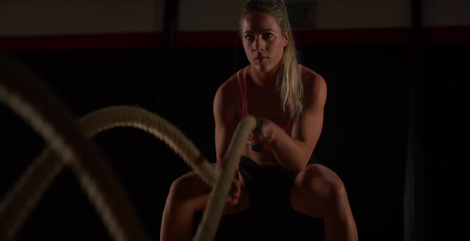 A woman crouches pulling ropes