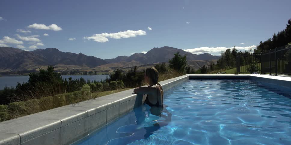 A woman is in her pool looking at a view