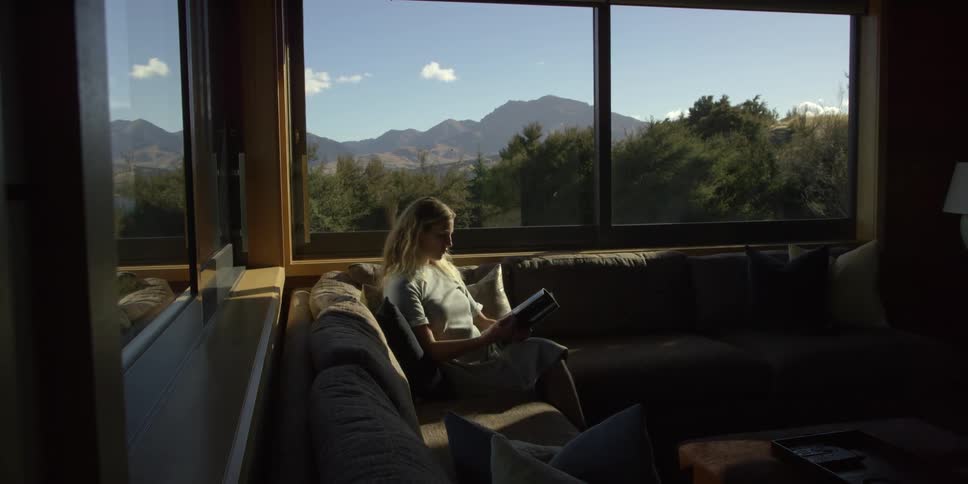 A woman is sitting on the couch reading