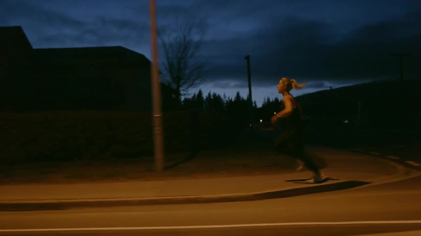 A woman runs down the dark road at dawn