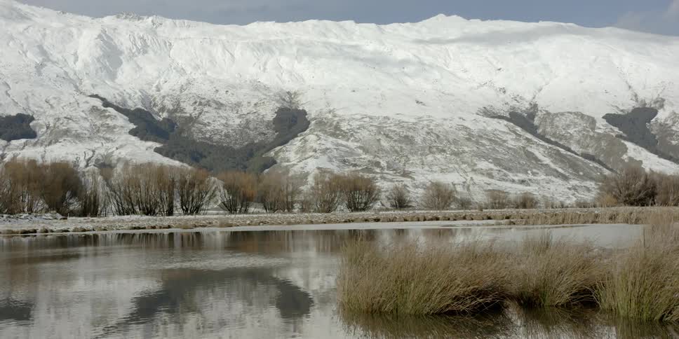 Lake flows in front of a large snowy mountain