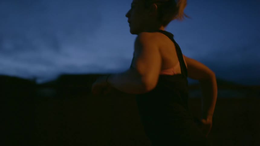 A woman jogs in a neighborhood at night