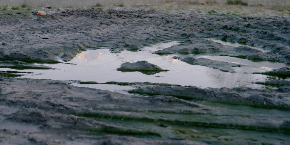 A puddle lays on the muddy ground