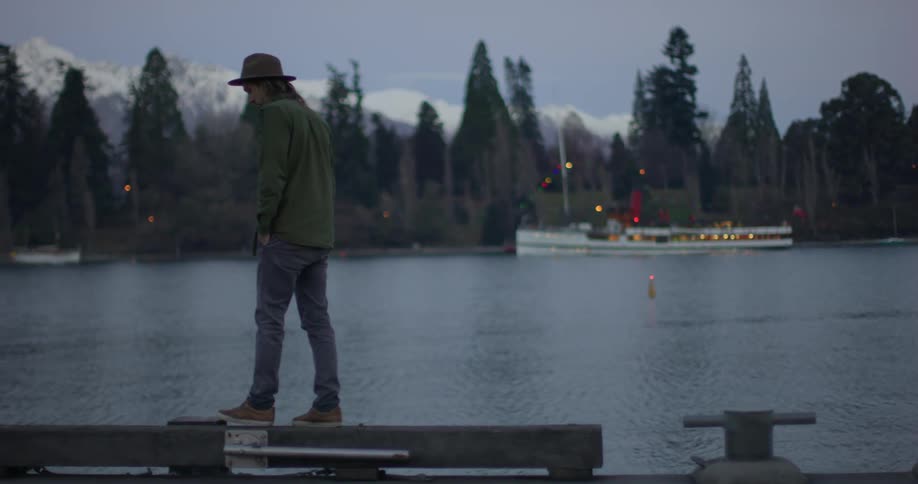A man walks on a beam near the water