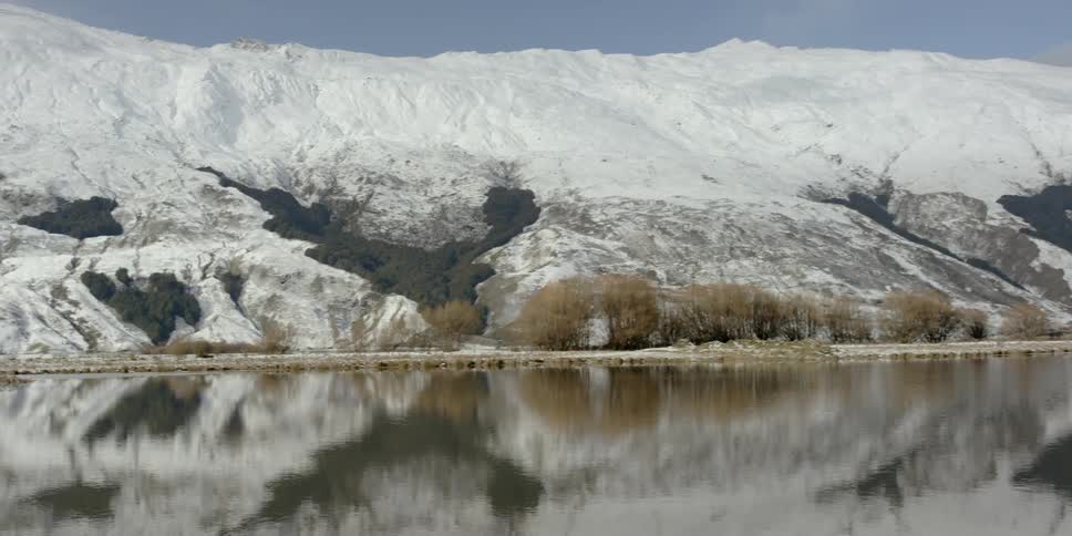Snow covered mountains are reflected in the lake surface