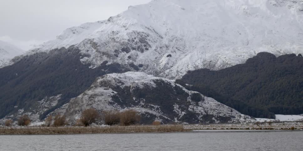 A lake ripples near a snowy mountain