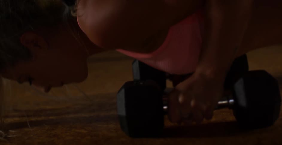 A woman is doing pushups on barbells