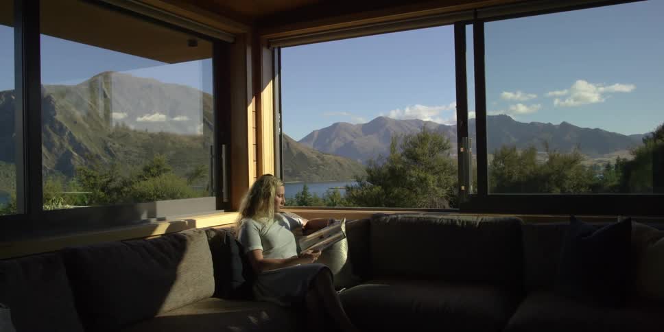 A woman reads a magazine in a lake house