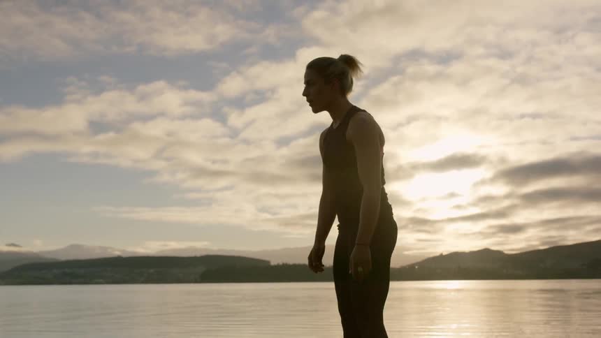 Woman stretches outside next to a lake