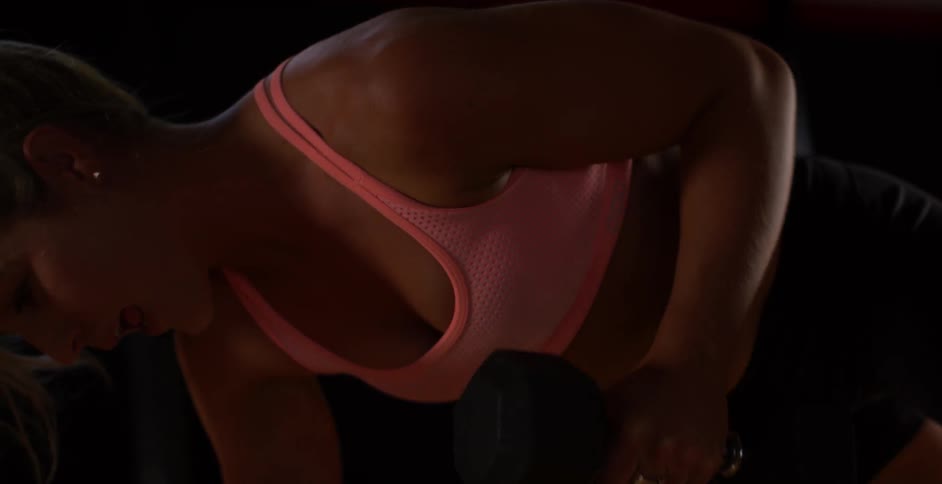A woman works out with dumbbells on a gym floor