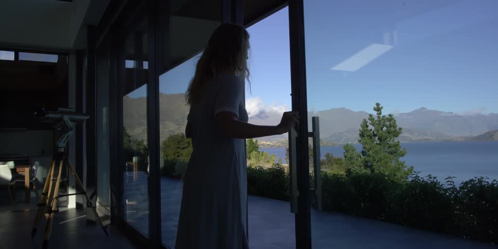 A woman exits her home to look at the lake