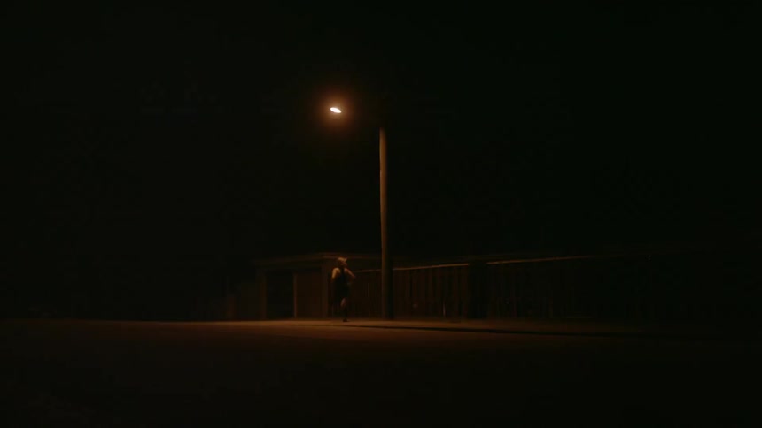 A person runs beneath a street lamp at night