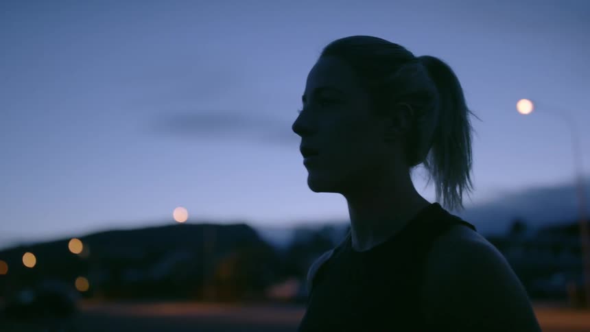 Woman stands outside at twilight