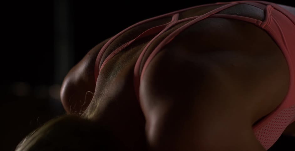 A woman bends over while wearing a sports bra